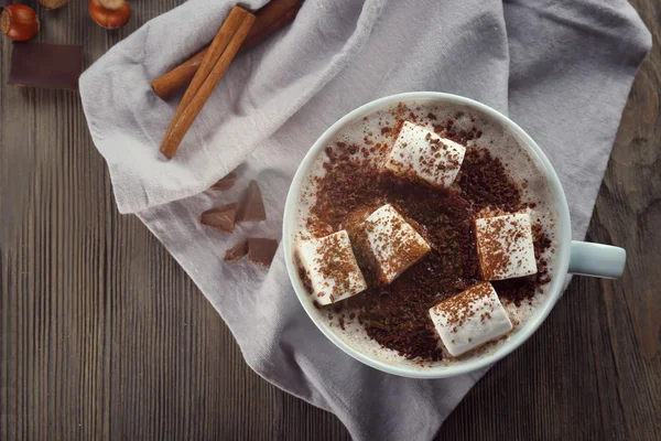 Tasse heißen Kakao mit Marshmallow, Zimt und Nüssen auf blauer Baumwollserviette, Nahaufnahme — Stockfoto