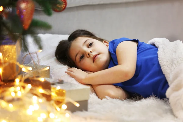 Досить маленька дівчинка спить на затишному дивані в різдвяній прикрашеній кімнаті — стокове фото