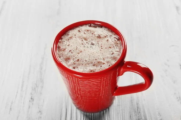 Copo vermelho de cacau quente no fundo de madeira — Fotografia de Stock