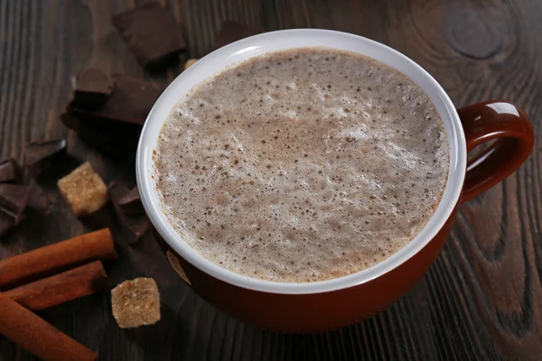 Tasse heißen Kakao mit Zimt und Süßigkeiten auf Holzgrund, Nahaufnahme — Stockfoto