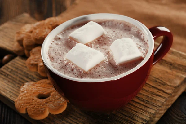 Чашка горячего какао с печеньем и орехами на деревянной доске, крупным планом — стоковое фото