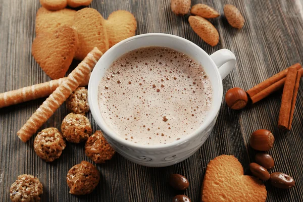 Tasse heißen Kakao mit Zimt, Mandeln und herzförmigen Plätzchen auf Holztisch — Stockfoto