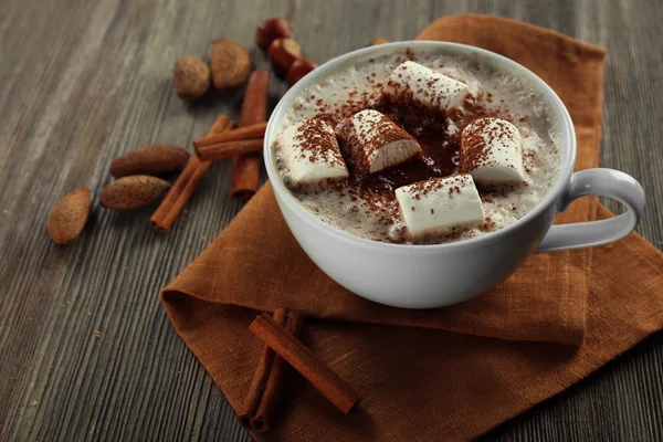 Tazza di cacao caldo con marshmallow, cannella e noci su tovagliette di cotone marrone, primo piano — Foto Stock