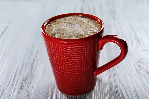 Red cup of hot cacao on wooden background — Stock Photo, Image