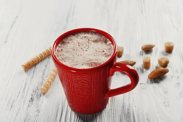 Червона чашка гарячого какао та цукерки на дерев'яному фоні — стокове фото