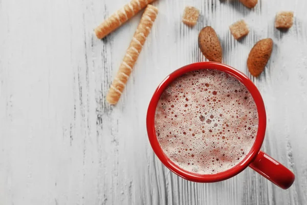 Červené šálek horkého kakaa a sladkosti na dřevěné pozadí — Stock fotografie