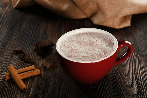 Cangkir coklat panas dengan kayu manis dan permen di latar belakang kayu, tutup — Stok Foto
