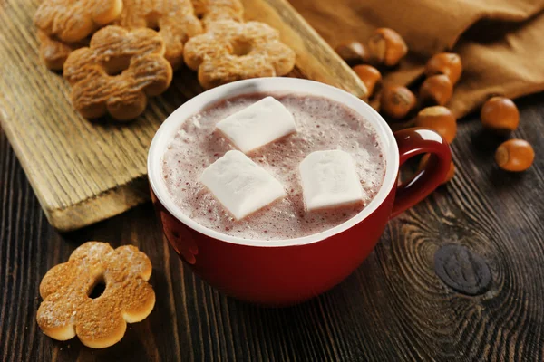 Tasse heißen Kakao mit Keksen und Nüssen auf Holzplatte, Nahaufnahme — Stockfoto