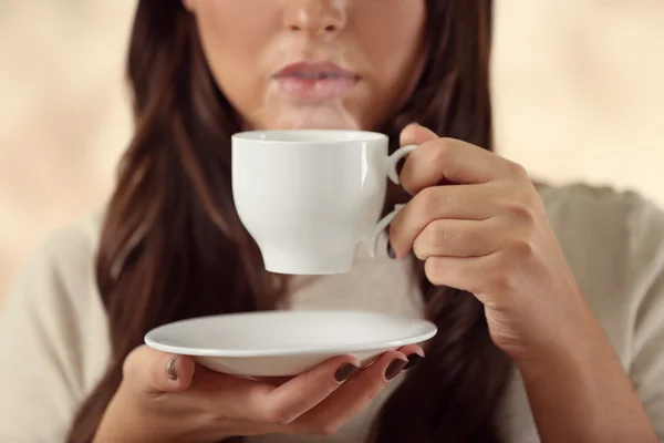 Portrait de jeune belle femme avec une tasse de café sur fond rose flou, gros plan — Photo