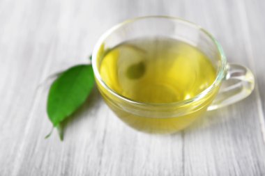 Cam bardak çay gri ahşap zemin üzerine yeşil yaprakları ile