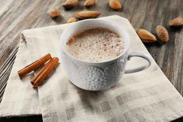 Secangkir coklat panas pada serbet kapas dengan kayu manis dan almond — Stok Foto