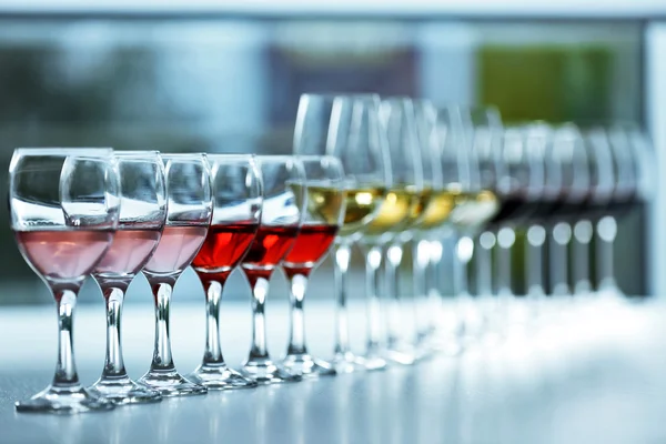 Pohárky s bílou, červená a růžová vína na dřevěný stůl na světlé pozadí — Stock fotografie