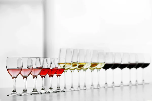 Wineglasses with white, red and pink wine on wooden table on bright background — Stock Photo, Image