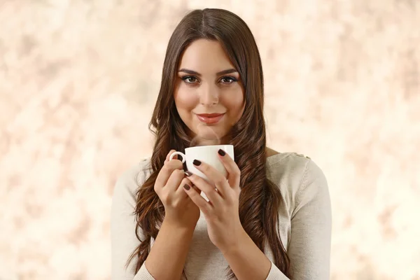 Портрет молодої красивої жінки з чашкою кави на рожевому розмитому фоні — стокове фото