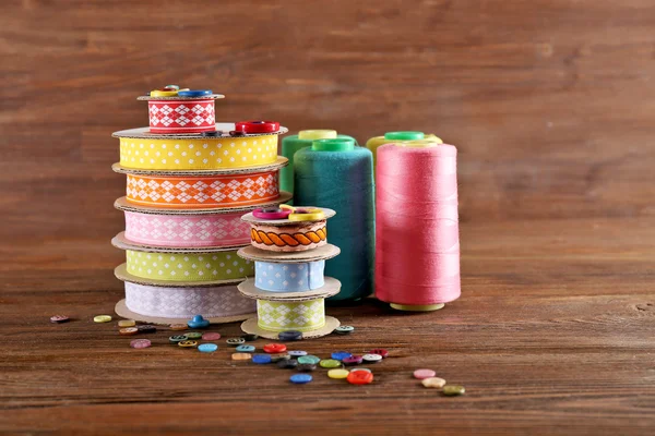 Spools of color ribbon and buttons on wooden background — Stock Photo, Image