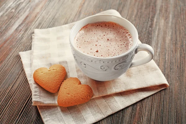 Cup of hot cacao with heart shaped cookies on cotton serviette