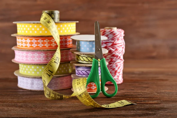 Spools of color ribbon with scissors on wooden background — Stock Photo, Image