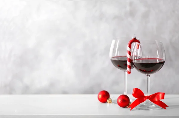 Dvě sklenky vína s vánoční doplňky na pozadí šedé zdi — Stock fotografie
