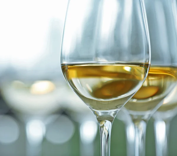 Gafas de vino con vino blanco y tinto sobre mesa de madera sobre fondo brillante —  Fotos de Stock