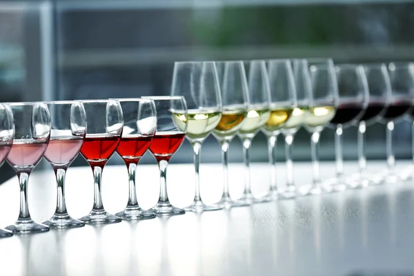 Виноградні келихи з білим, червоним і рожевим вином на дерев'яному столі на яскравому фоні — стокове фото