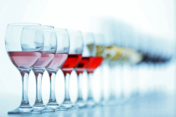 Виноградні келихи з білим, червоним і рожевим вином на дерев'яному столі на яскравому фоні — стокове фото
