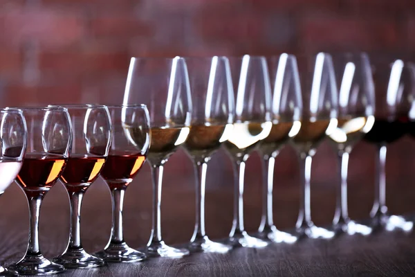 Vinhos com vinho branco, tinto e rosa na mesa de madeira no fundo do tijolo da parede — Fotografia de Stock