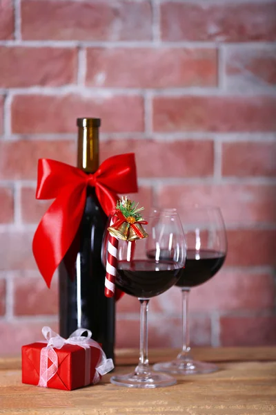 Flaska rött vin och glas med julklappar på väggen bakgrund — Stockfoto