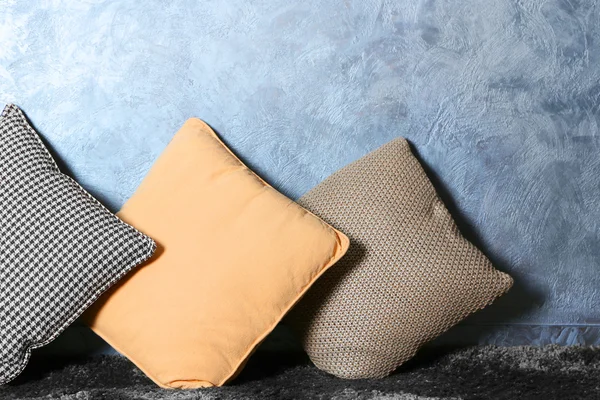 Poucos travesseiros no fundo da parede cinza — Fotografia de Stock