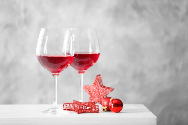 Dos copas de vino tinto con accesorios navideños sobre fondo gris — Foto de Stock