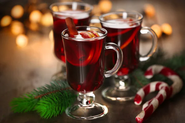 Glühwein mit Gewürzen und Weihnachtsbaum auf Holzgrund — Stockfoto