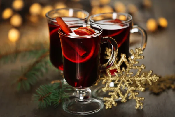 Mulled wine with spices and Christmas tree on wooden background — Stock Photo, Image