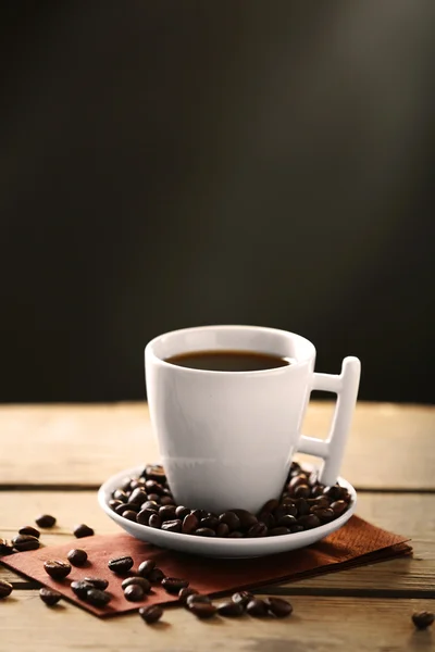 Kopje koffie en koffie korrels op houten tafel, op grijze achtergrond — Stockfoto