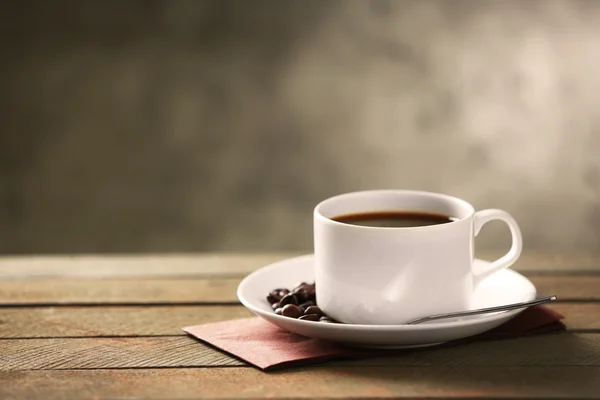Kopje koffie en koffie korrels op houten tafel, op grijze achtergrond — Stockfoto