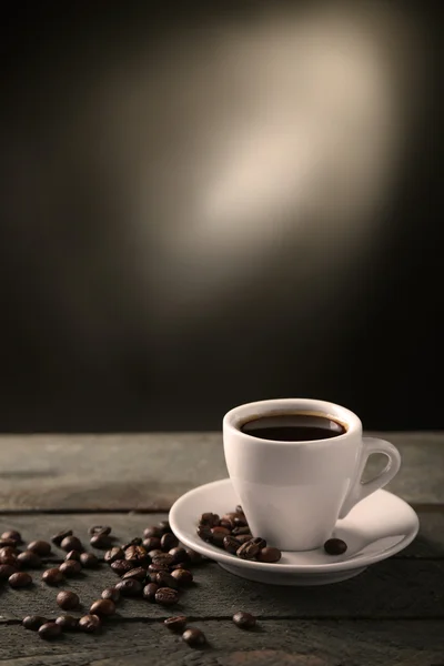 Cup of coffee and coffee grains on wooden table, on gray background — Stock Photo, Image