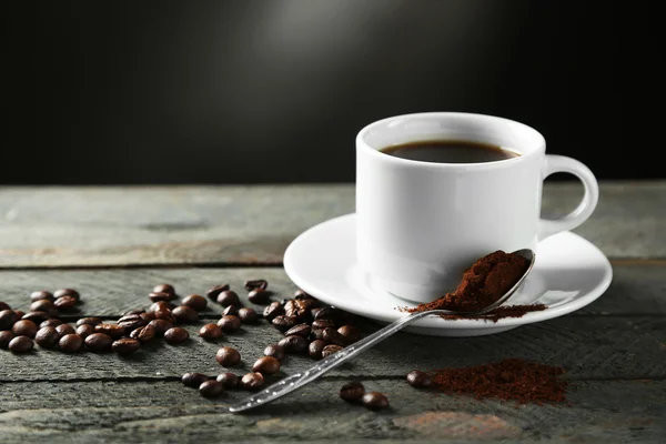 Tazza di caffè e chicchi di caffè su tavolo di legno, su sfondo grigio — Foto Stock