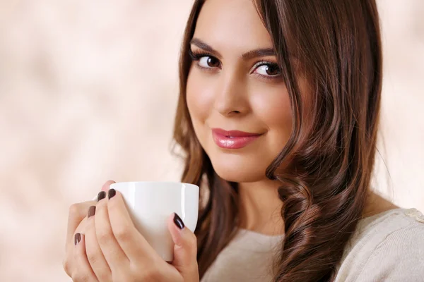 Portret van lachende mooie vrouw met een kopje koffie op roze onscherpe achtergrond — Stockfoto