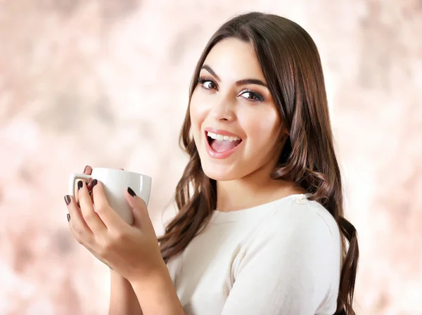 Portrait de jolie femme souriante avec une tasse de café sur fond rose flou — Photo
