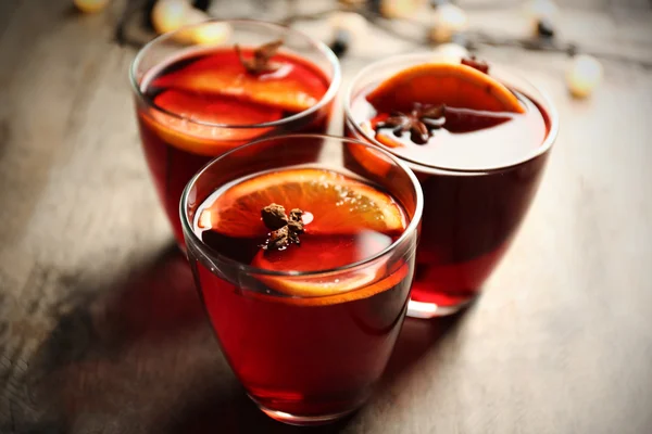 Glühwein mit Gewürzen und Weihnachtsbaum auf Holzgrund — Stockfoto