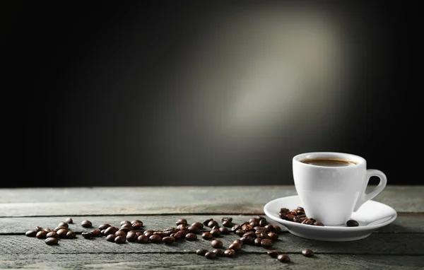 Kopje koffie en koffie korrels op houten tafel, op grijze achtergrond — Stockfoto