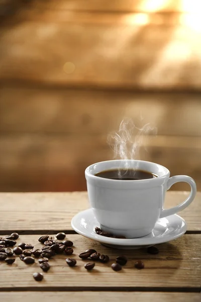 Tasse Kaffee und Kaffeekörner auf Holzgrund — Stockfoto
