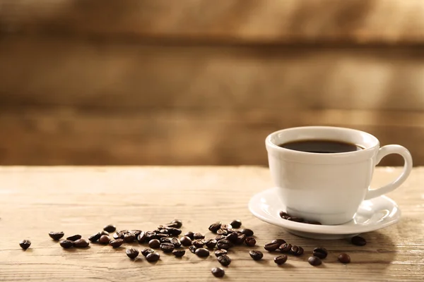 Filiżankę kawy i ziarna kawy na drewniane tła — Zdjęcie stockowe