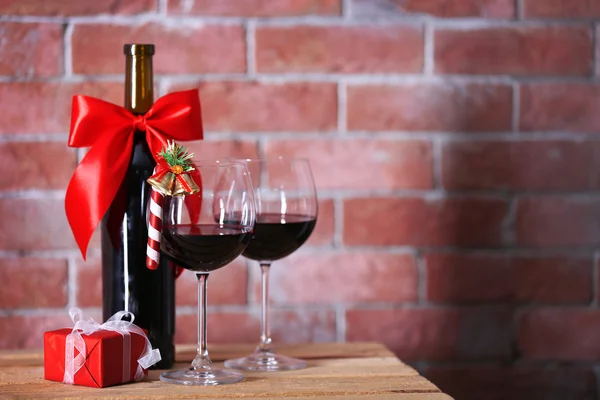 Flaska rött vin och glas med julklappar på väggen bakgrund — Stockfoto