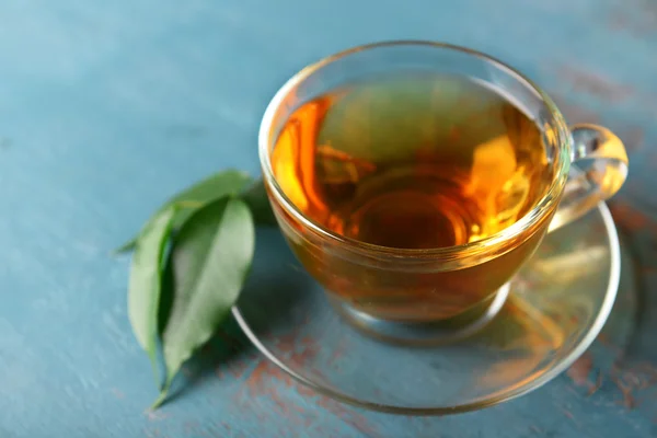 Taza de té con hojas verdes sobre fondo azul de madera — Foto de Stock