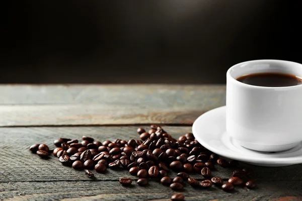 Copa de granos de café y café sobre mesa de madera, sobre fondo gris — Foto de Stock