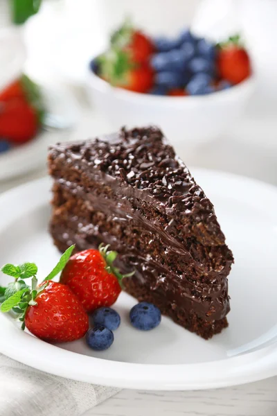 Chocolate cake met chocolade en verse bessen op plaat, op lichte achtergrond — Stockfoto