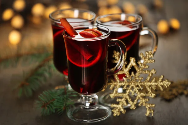 Glühwein mit Gewürzen und Weihnachtsbaum auf Holzgrund — Stockfoto