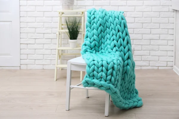 Вязанное шерстяное одеяло на стуле, на домашнем внутреннем фоне — стоковое фото