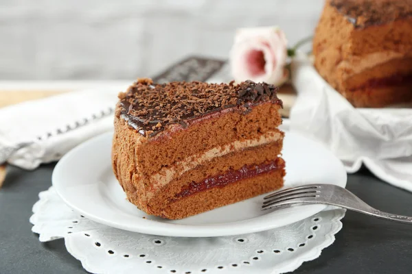 Нарізаний шоколадний торт на тарілці, на дерев'яному фоні столу — стокове фото