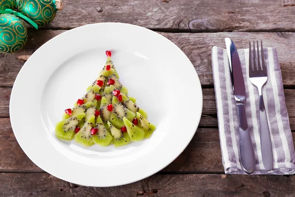 Árvore de abeto de Natal feita de kiwi, no prato, close-up — Fotografia de Stock