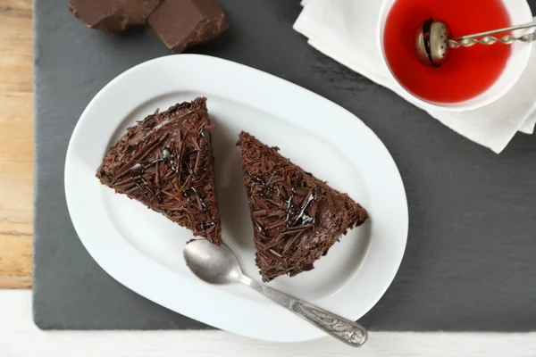 Sliced chocolate cake on plate, on wooden table  background — Stock Photo, Image